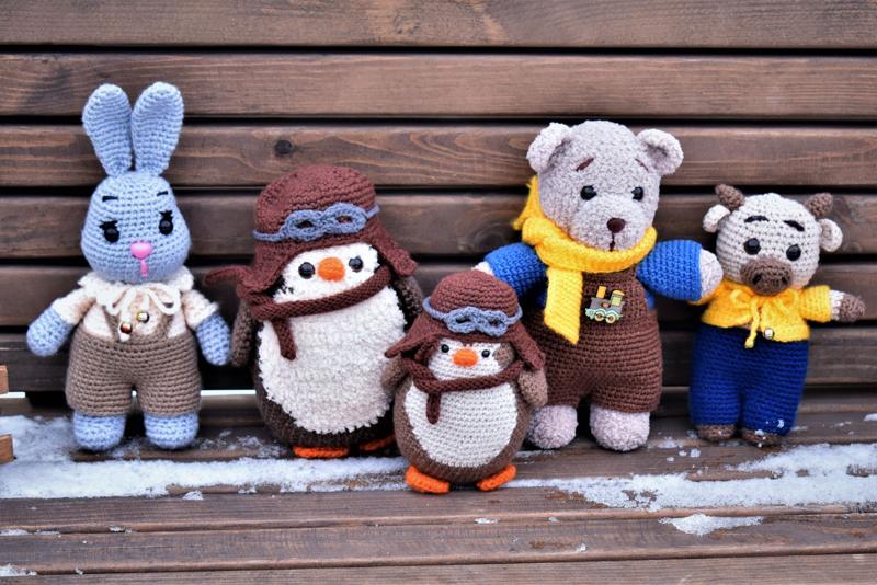 A row of crochet animals in little outfits on a wooden bench
